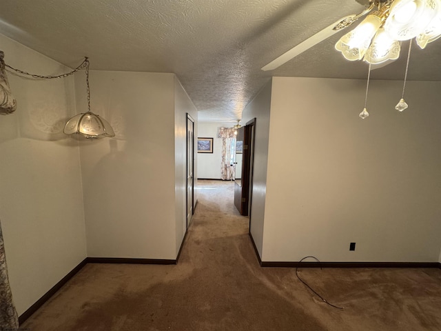 hall featuring baseboards, carpet floors, and a textured ceiling