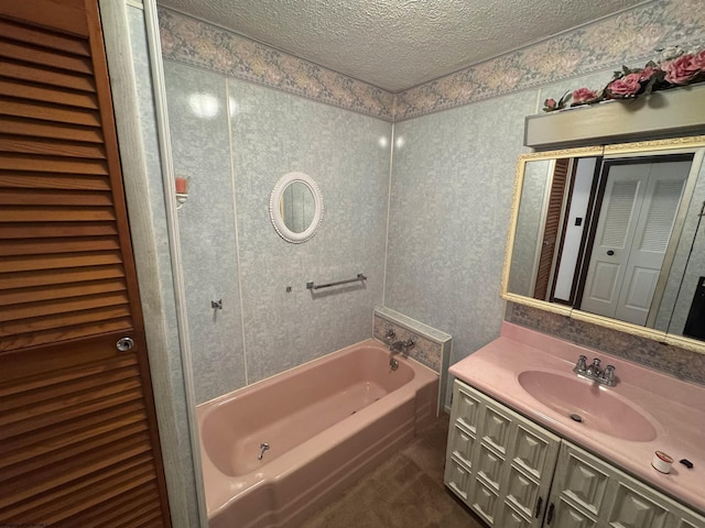 bathroom with a closet, a washtub, a textured ceiling, and vanity