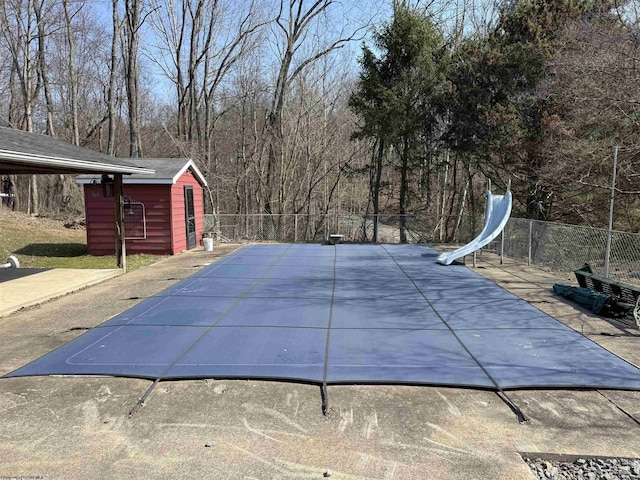 view of swimming pool featuring a storage unit, an outdoor structure, and fence