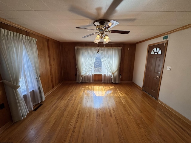 interior space featuring a ceiling fan, crown molding, wood finished floors, and visible vents