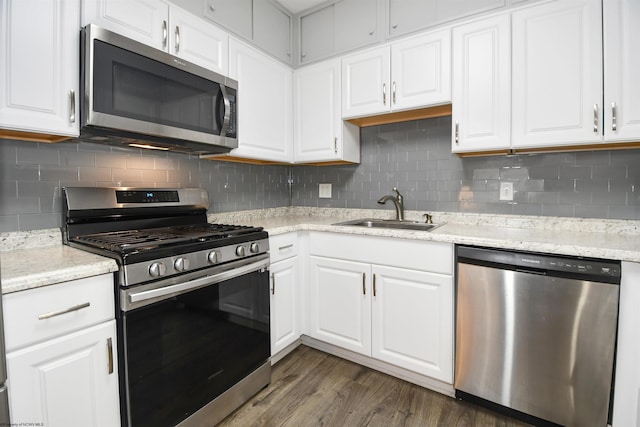 kitchen with dark wood-style flooring, appliances with stainless steel finishes, white cabinetry, and a sink