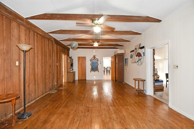 empty room with beamed ceiling, baseboards, a ceiling fan, and wood finished floors