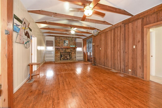 unfurnished living room with wood finished floors, visible vents, vaulted ceiling with beams, a fireplace, and ceiling fan