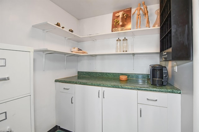 kitchen with dark countertops, white cabinetry, and open shelves