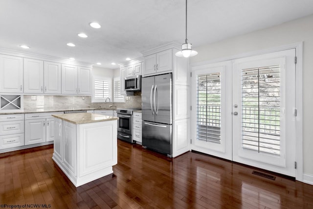 kitchen with dark wood finished floors, a sink, decorative backsplash, stainless steel appliances, and white cabinets