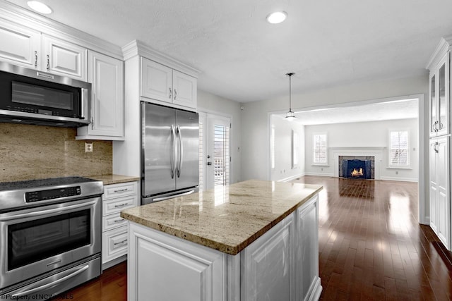 kitchen featuring a fireplace with flush hearth, appliances with stainless steel finishes, white cabinets, and dark wood-style flooring