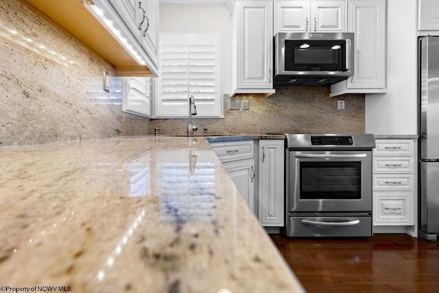 kitchen featuring a sink, decorative backsplash, stainless steel appliances, white cabinetry, and dark wood-style flooring