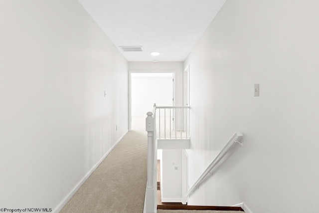 hall with baseboards, visible vents, an upstairs landing, and carpet floors