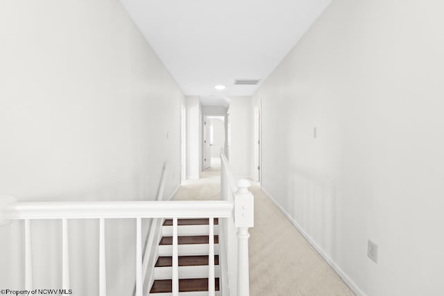 hallway featuring an upstairs landing, carpet, visible vents, and baseboards