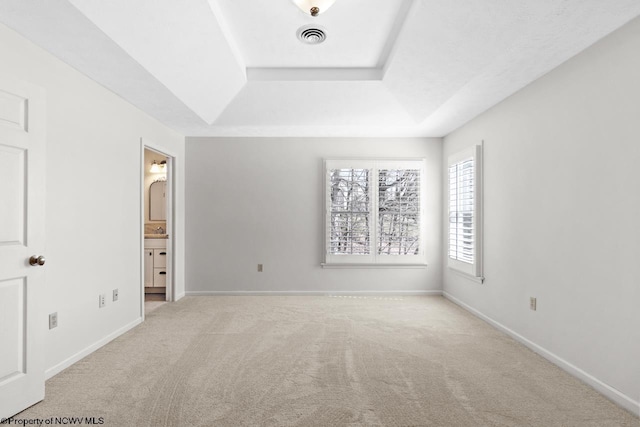 unfurnished bedroom featuring a raised ceiling, baseboards, visible vents, and light carpet