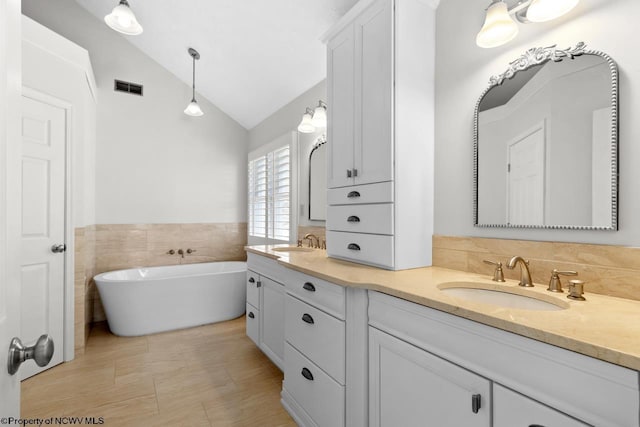 full bath featuring a sink, visible vents, lofted ceiling, and double vanity