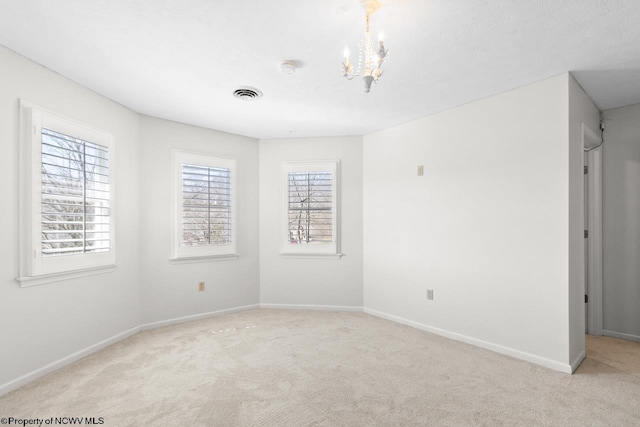 unfurnished room with visible vents, light colored carpet, baseboards, and an inviting chandelier