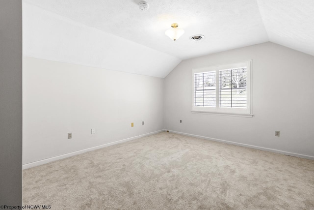 additional living space featuring visible vents, carpet, and vaulted ceiling