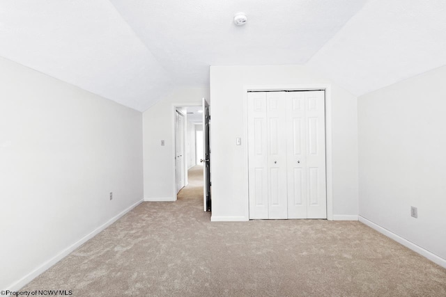 unfurnished bedroom featuring a closet, baseboards, carpet, and vaulted ceiling