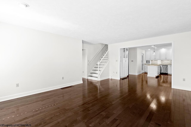 unfurnished living room with dark wood finished floors, visible vents, stairs, and baseboards