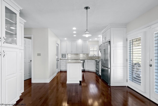 kitchen featuring decorative backsplash, stainless steel appliances, dark wood-style floors, white cabinetry, and a sink