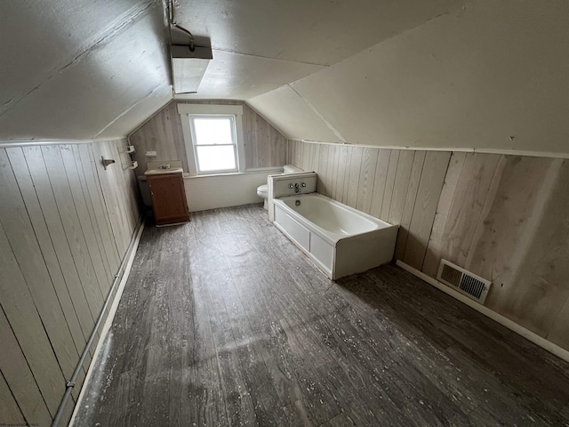 bonus room with visible vents, wood walls, lofted ceiling, and hardwood / wood-style flooring