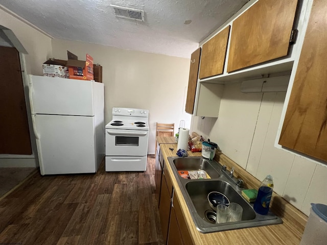 kitchen featuring visible vents, brown cabinets, a textured ceiling, dark wood-style floors, and white appliances