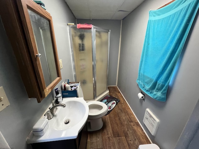 full bathroom featuring vanity, wood finished floors, a stall shower, a paneled ceiling, and toilet