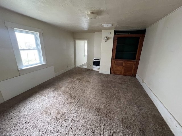 unfurnished living room with heating unit, visible vents, baseboards, carpet floors, and a textured ceiling