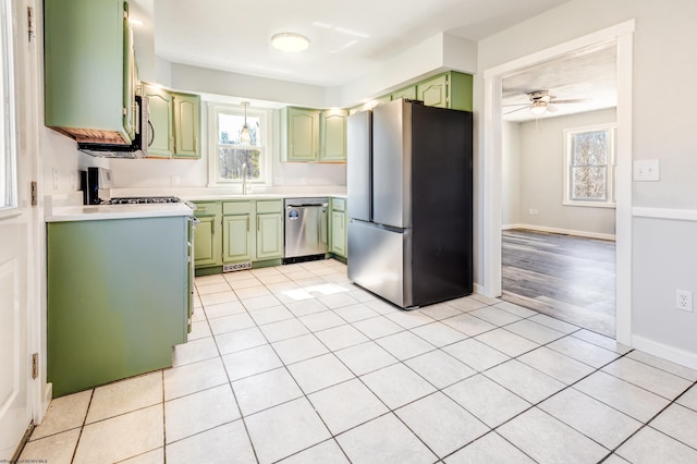 kitchen featuring green cabinetry, light countertops, a wealth of natural light, appliances with stainless steel finishes, and a sink