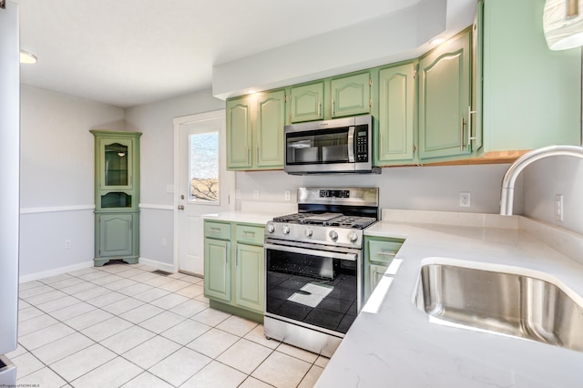 kitchen featuring appliances with stainless steel finishes, light countertops, green cabinets, and a sink