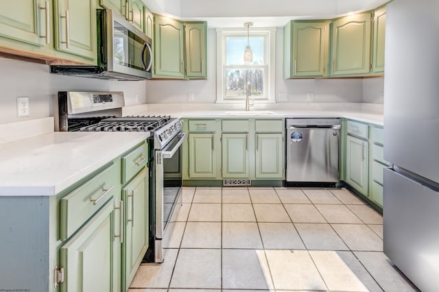 kitchen featuring green cabinets, light countertops, light tile patterned floors, stainless steel appliances, and a sink