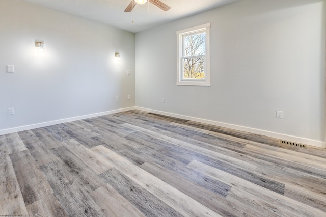 spare room featuring visible vents, wood finished floors, baseboards, and ceiling fan