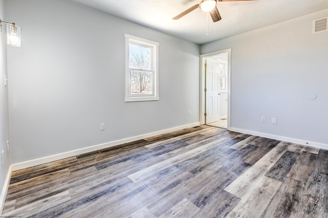 unfurnished room with visible vents, a ceiling fan, baseboards, and wood finished floors