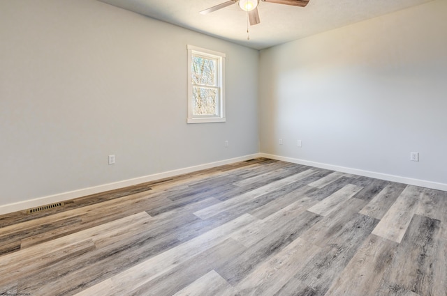 unfurnished room featuring ceiling fan, visible vents, baseboards, and wood finished floors