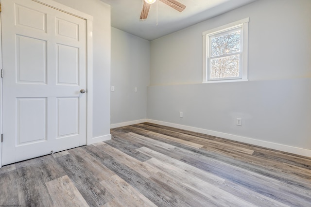 unfurnished bedroom featuring wood finished floors, baseboards, and ceiling fan