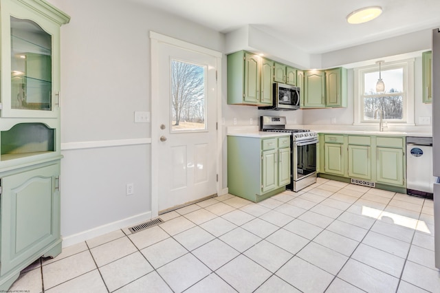 kitchen featuring a sink, light tile patterned floors, appliances with stainless steel finishes, and green cabinetry