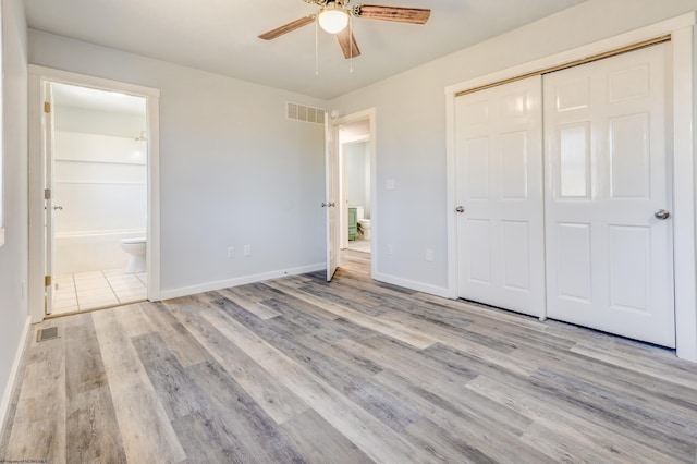 unfurnished bedroom featuring visible vents, ensuite bathroom, baseboards, and wood finished floors