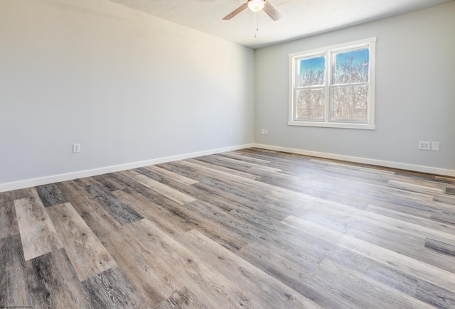 spare room with baseboards, wood finished floors, and a ceiling fan