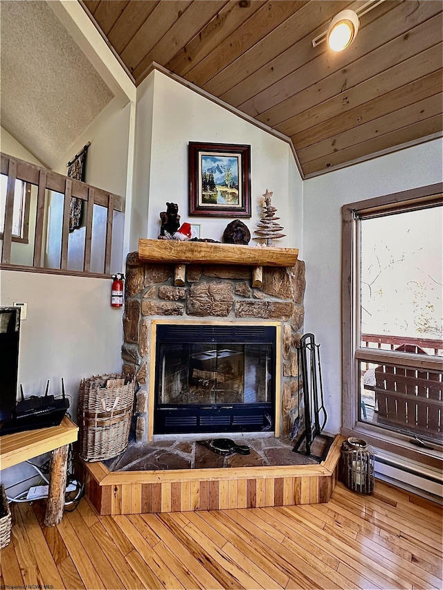 living room with hardwood / wood-style flooring, a stone fireplace, wooden ceiling, and vaulted ceiling