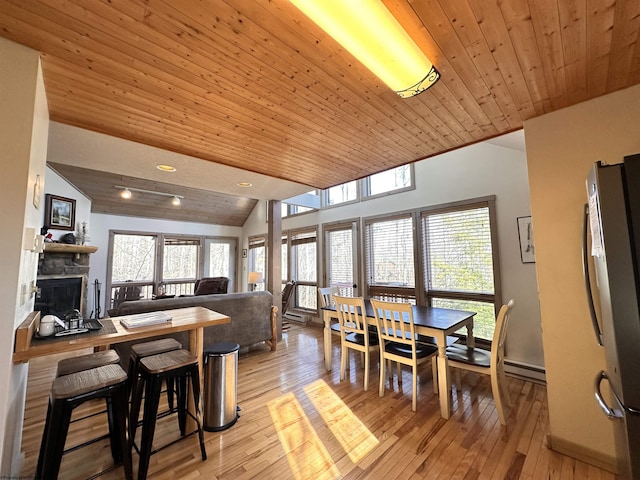 dining area featuring light wood-style floors, baseboard heating, wood ceiling, and vaulted ceiling