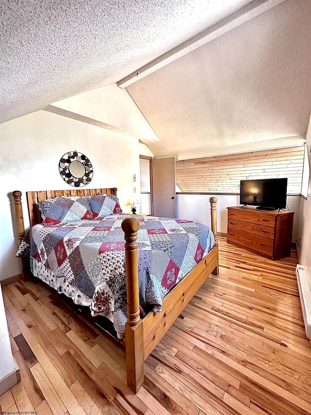 bedroom featuring a textured ceiling, vaulted ceiling with beams, and wood-type flooring