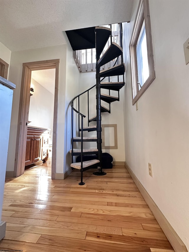 stairway featuring a textured ceiling, baseboards, and hardwood / wood-style flooring