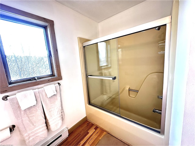 bathroom featuring shower / bath combination with glass door, a baseboard heating unit, baseboards, and wood finished floors