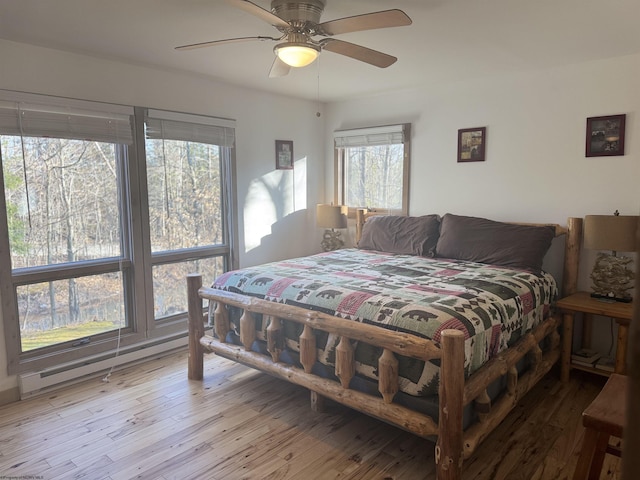 bedroom with ceiling fan, a baseboard radiator, and wood finished floors