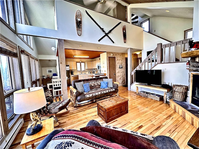 living room featuring a baseboard radiator, a healthy amount of sunlight, hardwood / wood-style floors, and stairway