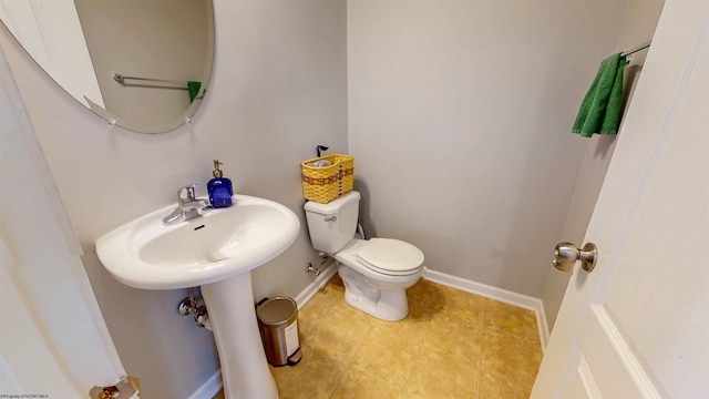 half bath featuring tile patterned floors, toilet, and baseboards