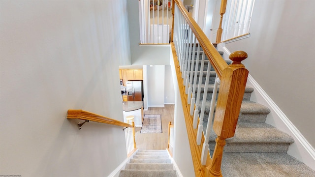 stairs featuring baseboards and a high ceiling