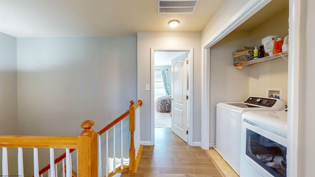 clothes washing area with separate washer and dryer, visible vents, light wood finished floors, and baseboards