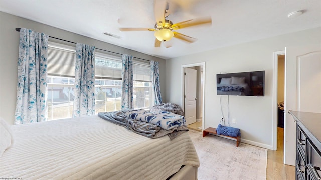 bedroom featuring visible vents, baseboards, light wood-style floors, and a ceiling fan