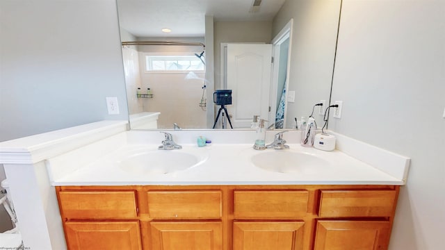 full bathroom featuring double vanity, a shower, and a sink