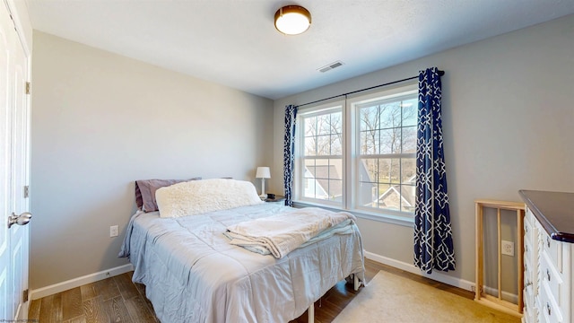 bedroom with visible vents, baseboards, and wood finished floors