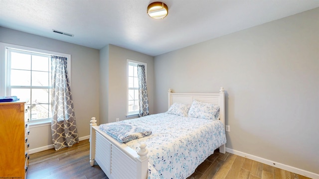 bedroom with visible vents, baseboards, and wood finished floors