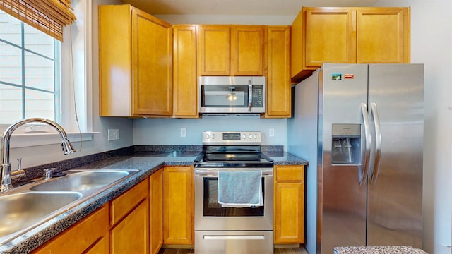 kitchen featuring a sink, dark countertops, brown cabinetry, and stainless steel appliances