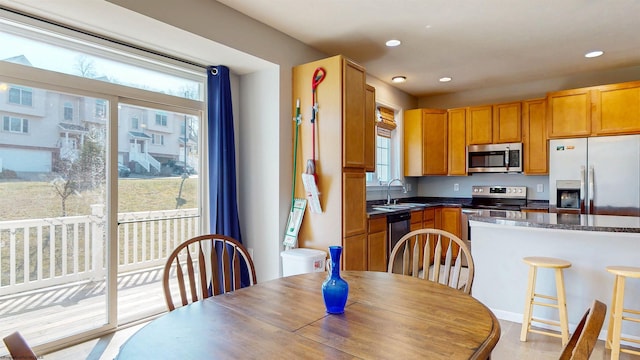 kitchen featuring a wealth of natural light, stainless steel appliances, dark countertops, and a sink